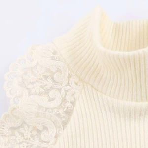 Detailed view of cream rib-knit top featuring a high neck and delicate floral lace shoulder