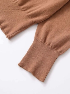 Detailed macro view showing the ribbed knit texture and stitching of the brown sweater sleeve