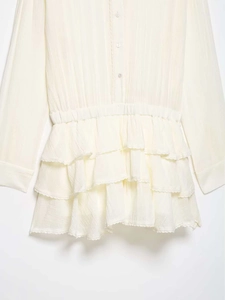 Detail showing cream tulle layered dress with delicate lace edges and tiered skirt design