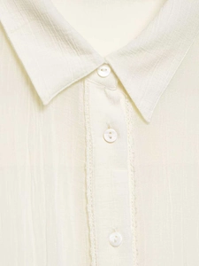 Detail of cream blouse featuring layered lace trim and elegant pearlescent buttons