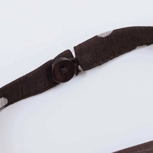 Detailed macro shot of coffee brown polka dot fabric with button and elastic loop closure