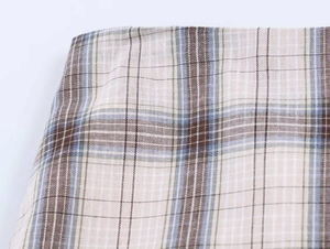 Detail shot of plaid fabric texture in beige, coffee, and light blue with fine stitching