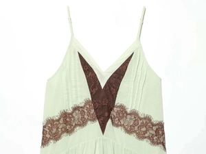 Close-up of contrast floral lace patchwork on light green mini slip dress fabric