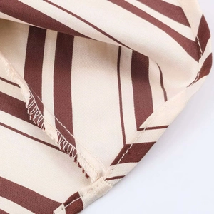 Detail of elegant striped midi dress showing red-brown twill fabric and fine stitching