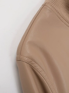 Close-up of beige leather jacket showing fine grain texture and ribbed knit collar detail