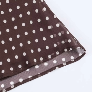 Detailed view of dark brown polka dot chiffon fabric with delicate rolled hem finish