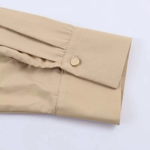 Détails macro des manches de robe kaki avec plis fins et bouton doré élégant