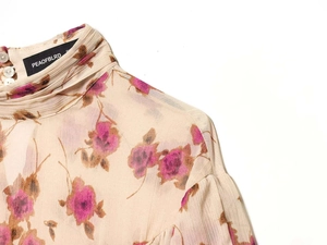 Close-up of floral print blouse featuring high ruffled collar and pearl back buttons
