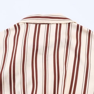 Detailed close-up of the shirt collar with elegant vertical brown stripes on beige fabric