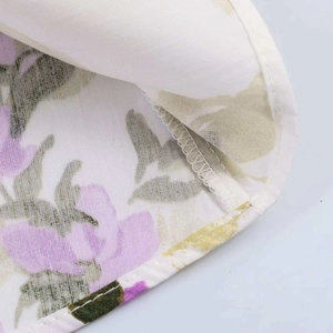 Close-up of floral print dress fabric with purple flowers and double-stitched hem detail