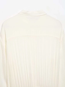 Detail shot of the back yoke and vertical pleated texture on a cream chiffon shirt