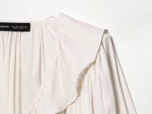 Detail der hellbeigen Satinbluse mit gestuften Rüschen und weicher Plissee-Stoffstruktur