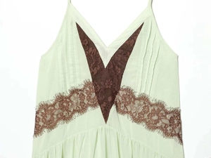 Detail shot of light green mini dress featuring brown eyelash lace patchwork and delicate straps