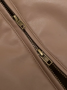 Close-up of pink leather jacket with bronze double-zip detail and fine texture