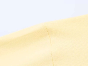 Macro view of stitching and knit texture on the shoulder of this light yellow top