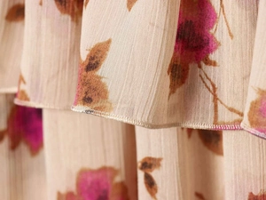 Close-up of floral pleated chiffon fabric showing delicate pink flower prints and hem