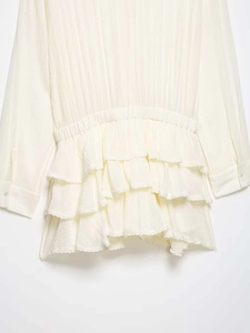 Detailed view of layered lace ruffles and pleated waist on an elegant cream chiffon dress