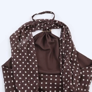 Detailed close-up of brown polka dot halter top featuring a gold ring connector and pleats