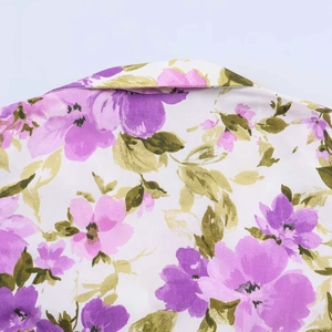 Detail shot of a floral print dress neckline with purple flowers on white fabric