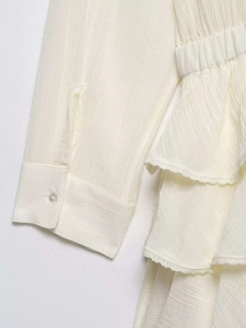 Detail of cream tulle dress featuring pleated texture and delicate lace-edged ruffles