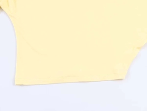Close-up detail of fine stitching and soft yellow knit texture on the fabric edge