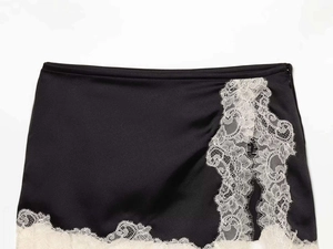 Détail de la jupe en satin noir avec ourlet en dentelle de cils blanche et fermeture éclair latérale