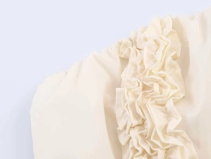 Detailopname van een beige midi-jurk met verticale ruches en geweven textuur