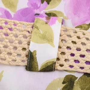 Close-up of floral print dress with a woven straw belt and reinforced stitching details