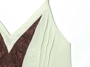 Detail of V-neckline with brown floral lace and vertical pleats on light green mini dress