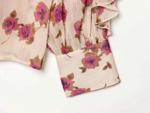 Detail of floral chiffon blouse featuring tiered ruffle sleeves and elegant smocked cuffs