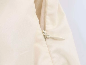 Detail of invisible zipper closure on a cream-colored midi dress with fine fabric texture
