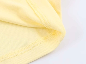 Detailed close-up of the professional overlock stitching on a yellow knit top