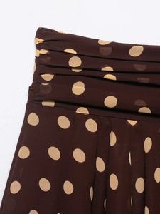 Detail of polka dot skirt featuring high-waist ruched pleats and retro brown fabric