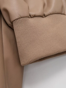 Macro view of camel faux leather jacket cuff with elastic knitted ribbed trim