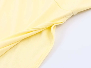 Detail view of smooth yellow knit fabric showing fine stitching and premium textile texture