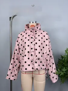 Detail of pink jacket with black polka dots featuring high collar and drawstring hem