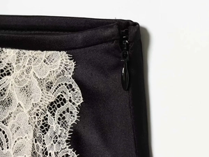 Gros plan sur une jupe en satin noir avec fermeture éclair invisible et dentelle blanche