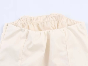 Detail van de crème midi-jurk met elastische taille en onzichtbare ritssluiting aan de zijkant