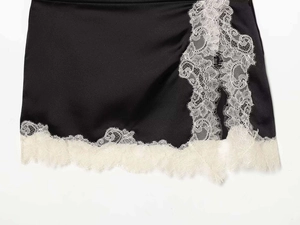 Gros plan sur l'ourlet de jupe en satin noir avec dentelle blanche et bordure de cils