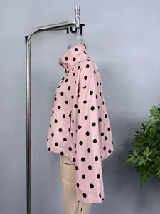 Detail of pink polka dot long sleeve jacket featuring adjustable drawstring and high neck collar
