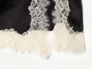 Détail de la bordure en dentelle de cils blanche sur une jupe courte en satin noir chic