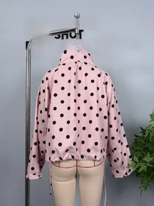 Detailed view of pink long-sleeved jacket with black polka dots and shirt collar