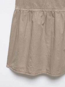 Close-up detail of khaki midi dress fabric showing pleats and ruffled hem textures