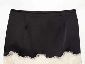 Vue détaillée d'une mini-jupe élégante en satin noir avec ourlet en dentelle blanche délicate