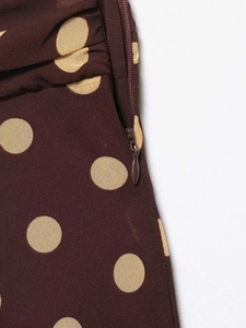Detailed view of invisible side zipper on a brown polka dot skirt with woven texture