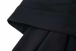 Detail of the high-waisted crossover design and twill texture on a black garment