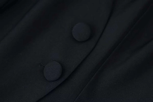 Detail of fabric texture and covered buttons on a black long-sleeve jacket