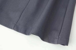 Vista detallada del dobladillo de tela tejida gris oscuro con costuras precisas y sarga