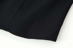 Detail view of the black long sleeve jacket showing neat rolled hem and woven fabric texture