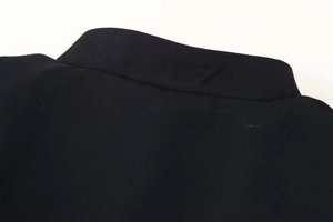 Detail shot of a sleek black high collar jacket with premium stitching and texture